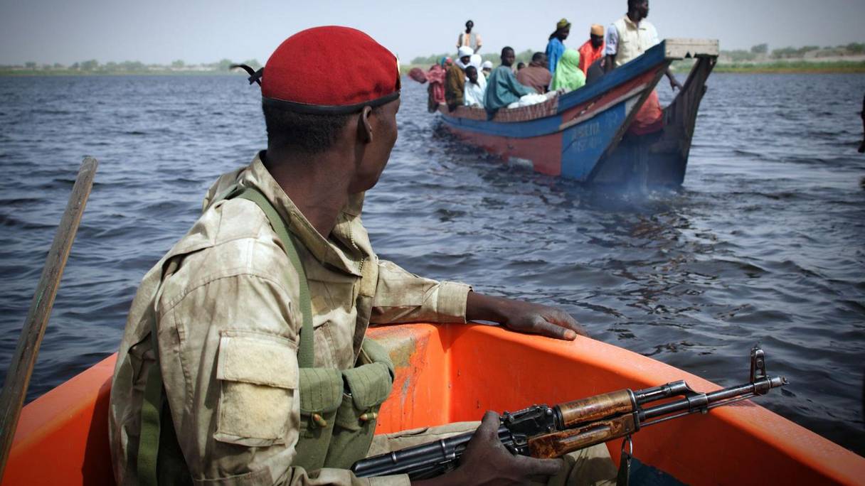 Un soldat tchadien surveillant la traversée d'une pirogue au niveau du lac. 