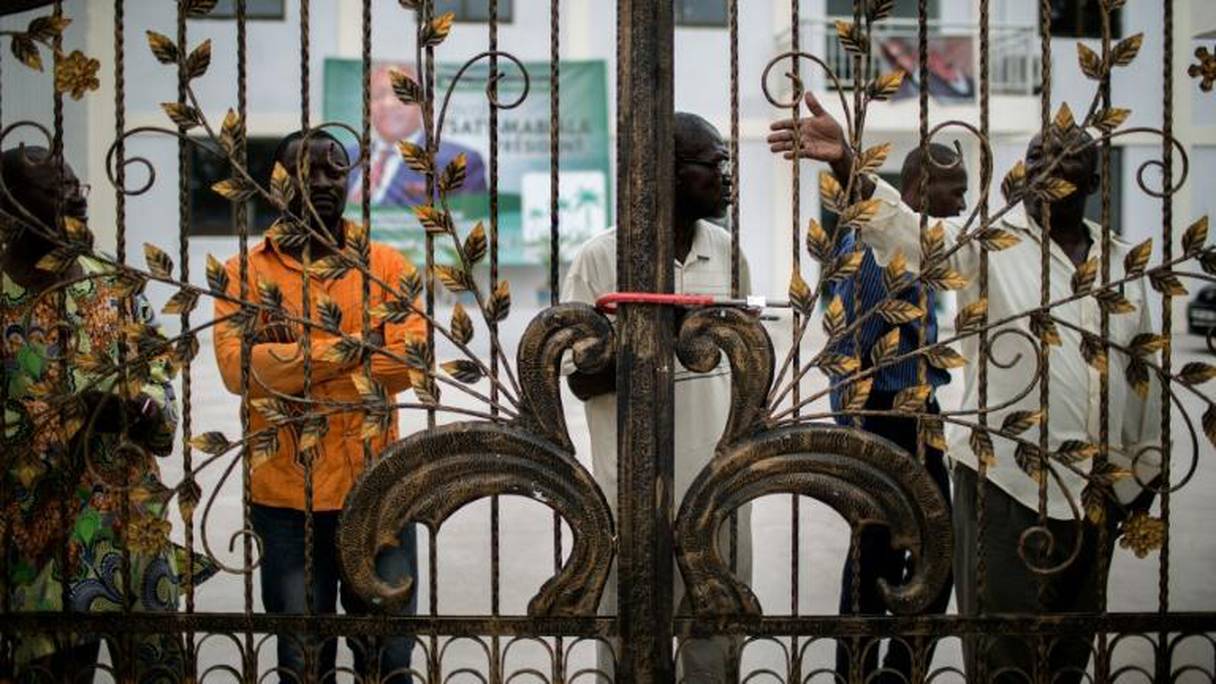 Des militants du parti d'opposition congolais UPADS derrière les grilles cadenassées du siège de leur parti à Brazzaville. 
© AFP MARCO LONGARI 
