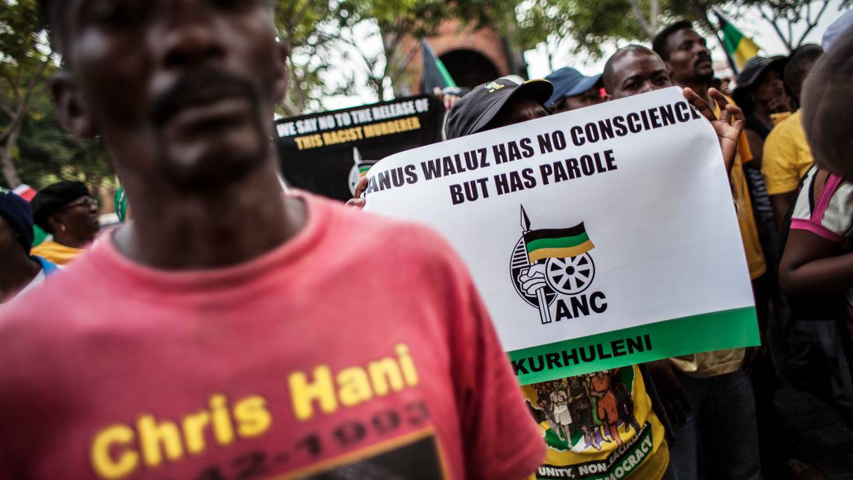 Des membres de l'African National Congress (ANC) manifestent devant la Cour constitutionnelle pour protester contre la libération conditionnelle accordée à Janusz Walus, l'assassin du héros anti-apartheid Chris Hani, le 14 mars 2016.