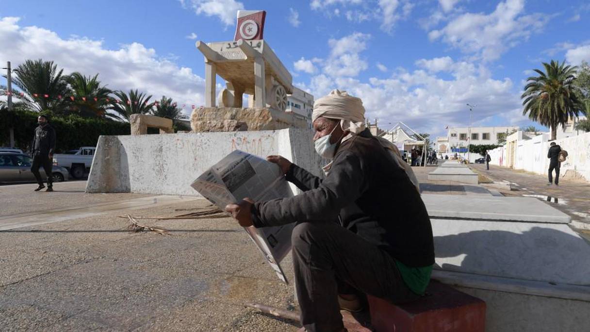 A Sidi Bouzid, centre de la Tunisie, un homme en masque de protection lisant le journal devant la statue dédiée à Mohamed Bouazizi, le marchand ambulant mort en 2011. 