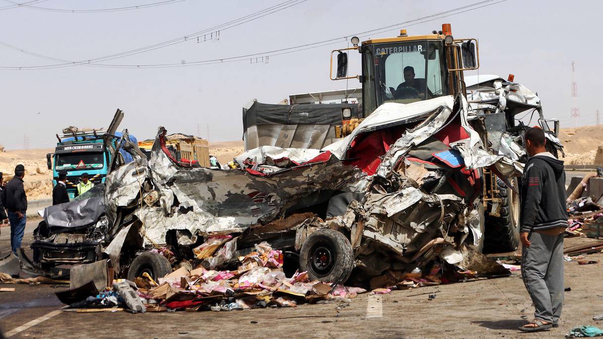 Des ouvriers enlèvent l'épave d'une voiture sur le site d'un accident de la route près de la ville d'Al-Saff, dans la province de Gizeh, au nord du Caire, à environ 40 kilomètres au nord de la capitale, le 26 mars 2020, qui a fait plusieurs morts et blessés.