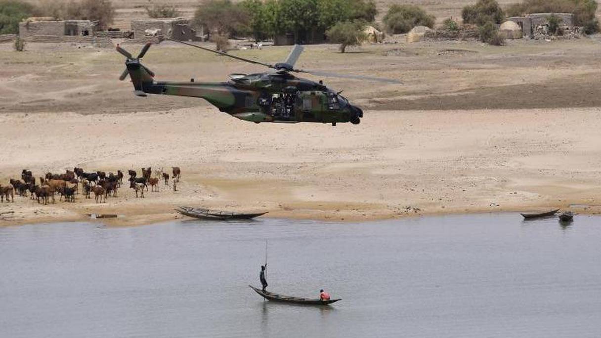 Un hélicoptère de la force Barkhane survolant une pirogue sur le fleuve Niger. 