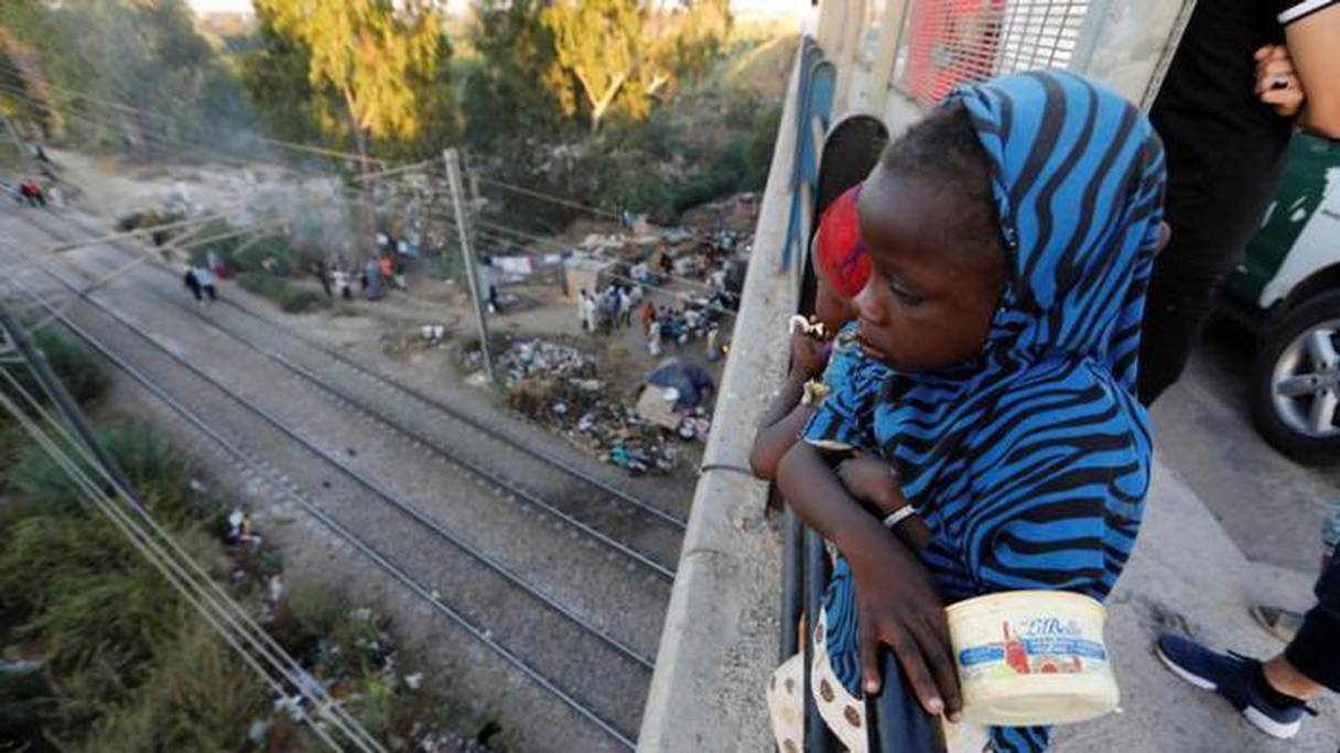 Une jeune migrante sur un pont routier surplombant un camp de fortune à la périphérie d'Alger. 