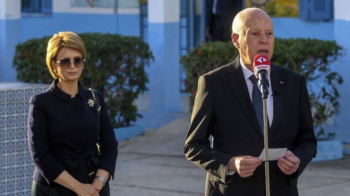 Accompagné de son épouse Ichraf Chebil, le président tunisien Kaïs Saïed à sa sortie d'un bureau de vote du district d'Ennasr, près de Tunis, le 17 décembre 2022, lors d'élections législatives caractérisées par un taux d'abstention record: 90%.
