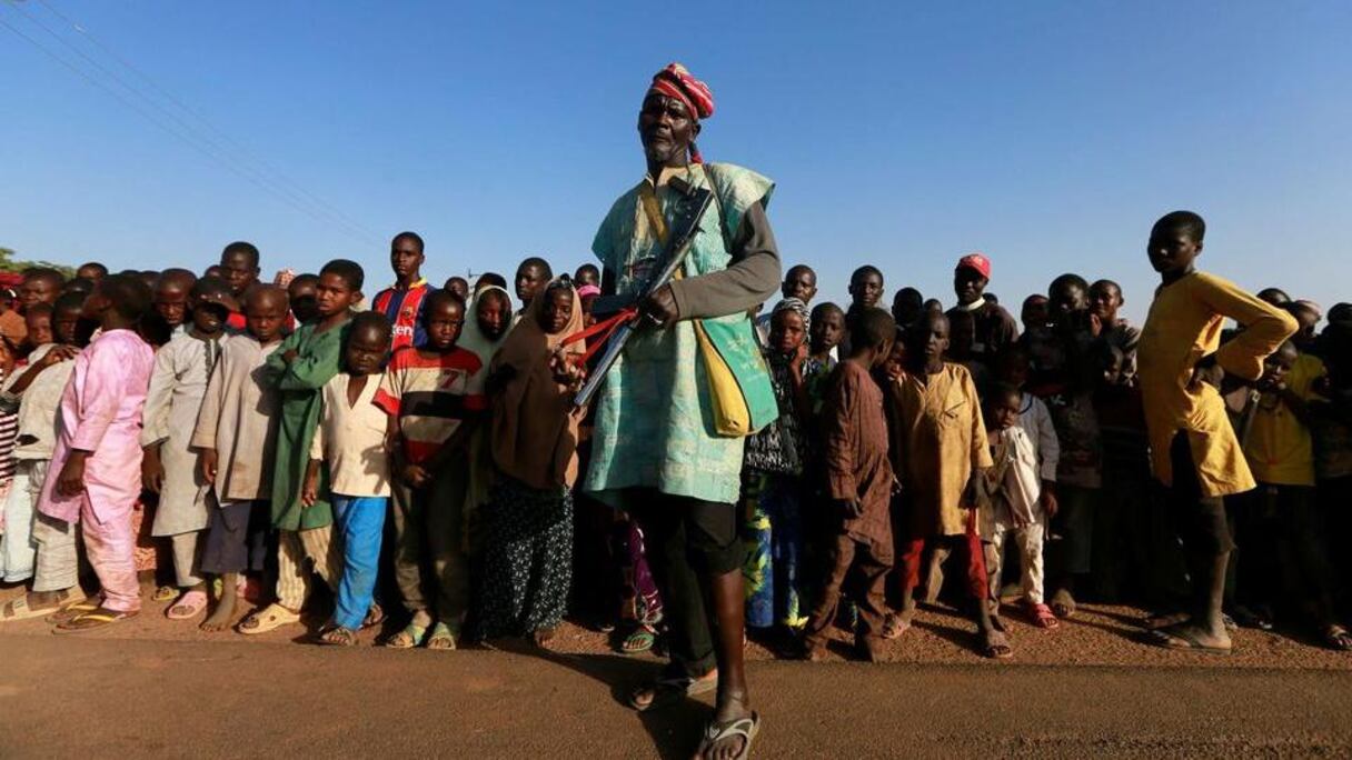 Un homme tenant une arme de fabrication artisanale, devant des enfants au nord du Nigeria.