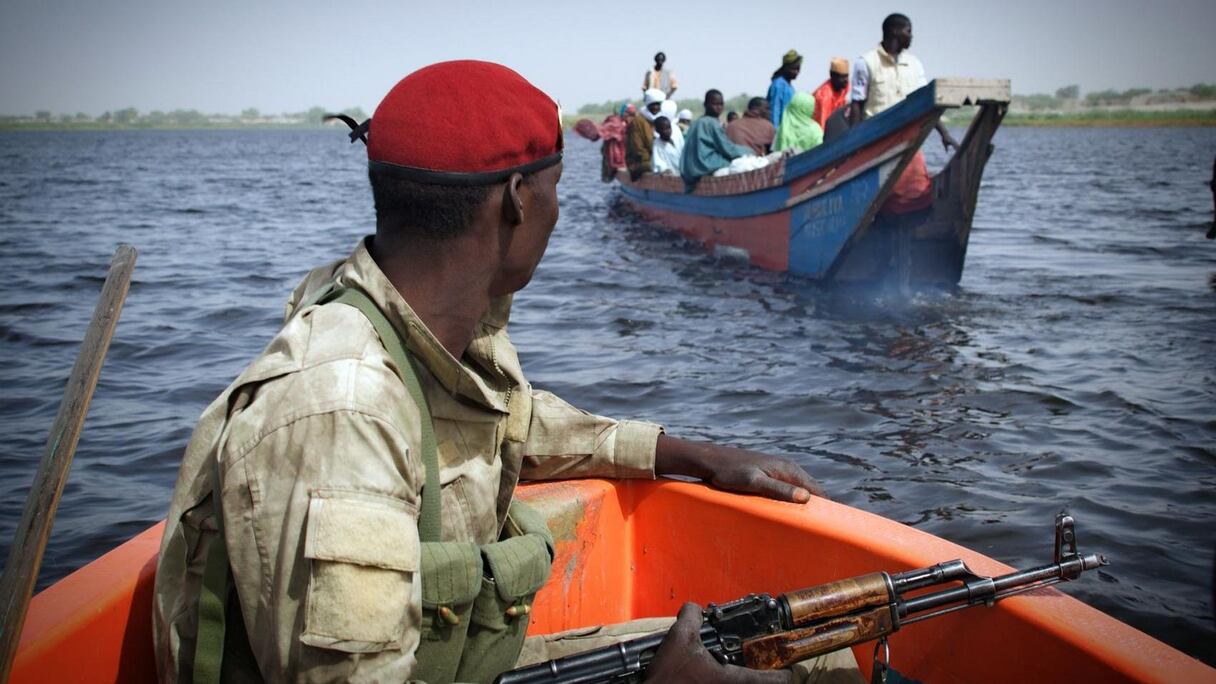 Un soldat tchadien surveillant la traversée d'une pirogue au niveau du lac.