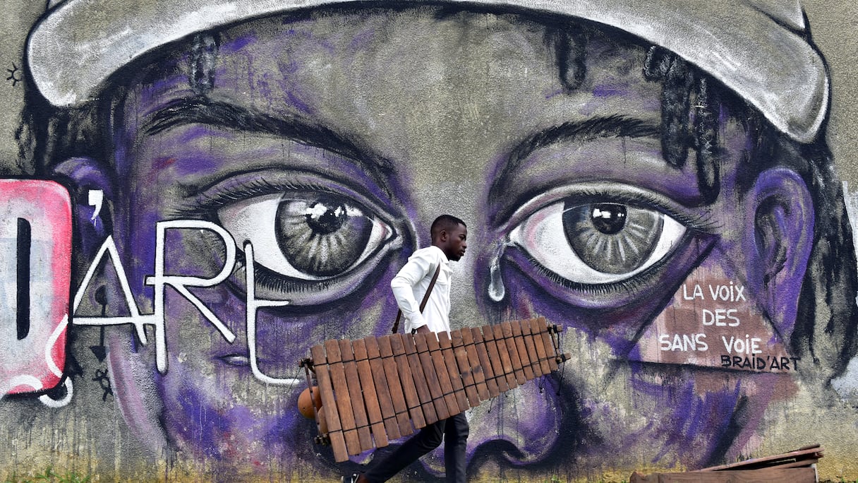 un étudiant avec un balafon, un xylophon en bois, dans la cour de l'Institut national supérieur des arts et de l'action culturelle à Abidjan