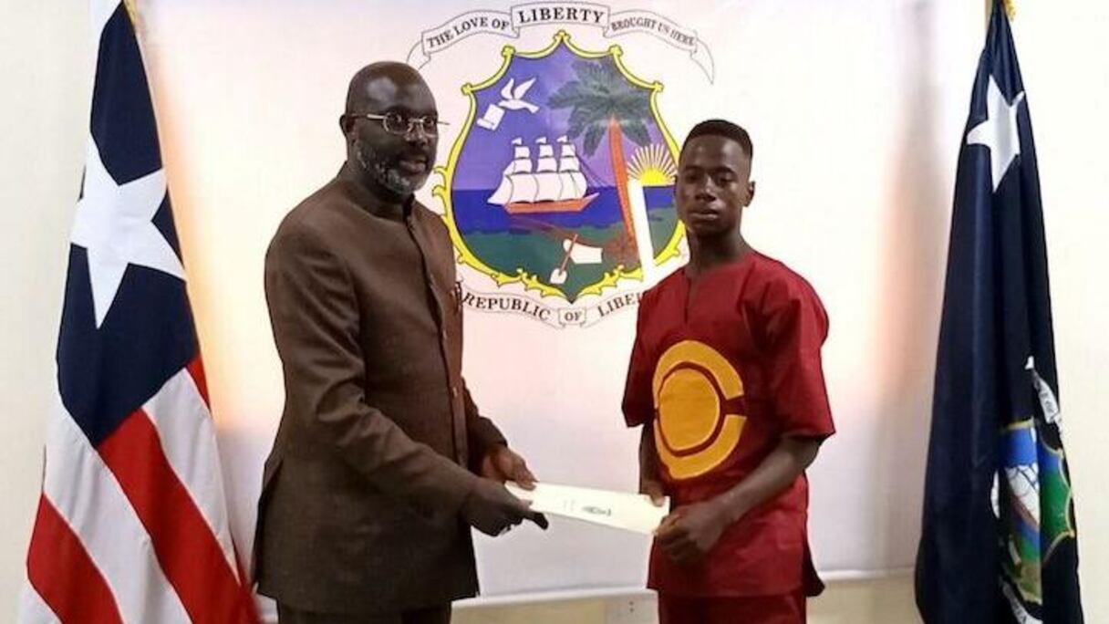 Le président du Liberia George Weah (à gauche) reçoit Emmanuel Tuloe, qui a récemment trouvé et rendu la somme de 50 000 dollars à sa propriétaire. Pour le remercier, le président lui a fait don de 10 000 dollars, d'un salaire de 500 dollars mensuel, de deux motocyclettes, et des frais de scolarité jusqu'au master.