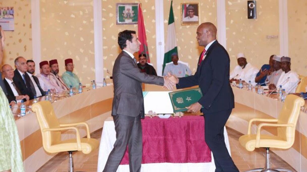 Mohamed Benchaaboun, PDG du groupe BCP, et Tony O. Elumelu, PDG d’Heirs Holdings, signant l’accord devant le roi Mohammed VI du Maroc et le président nigérian Muhammadu Buhari.