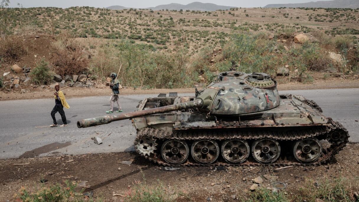 Dans cette photo prise le 20 juin 2021, des agriculteurs locaux marchent à côté d'un char de l'armée érythréenne qui est abandonné le long de la route à Dansa, au sud-ouest de Mekele dans la région du Tigré, en Éthiopie.