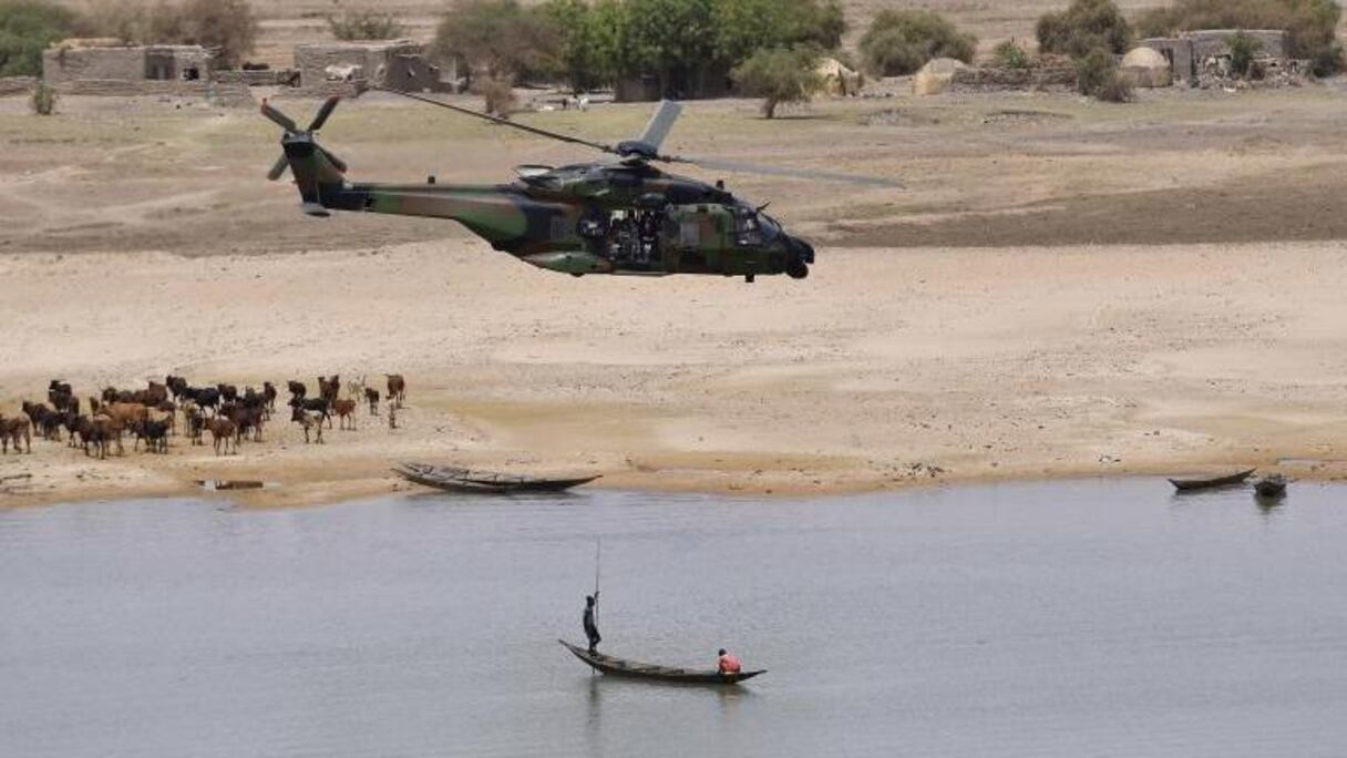Un hélicoptère de la force Barkhane survolant une pirogue sur le fleuve Niger.