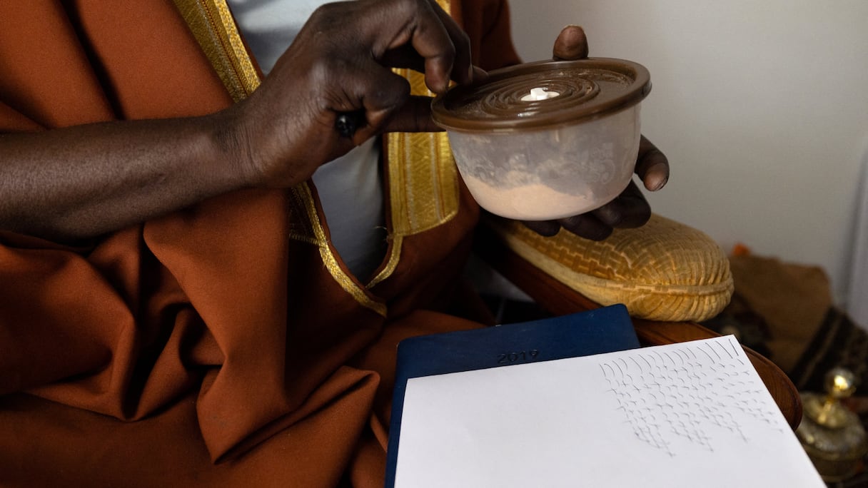 Le guérisseur africain Cheick Issa note en géomantique ce qu'il ressent lors de la consultation avec l'un de ses clients, le 16 septembre 2023, à Paris.
