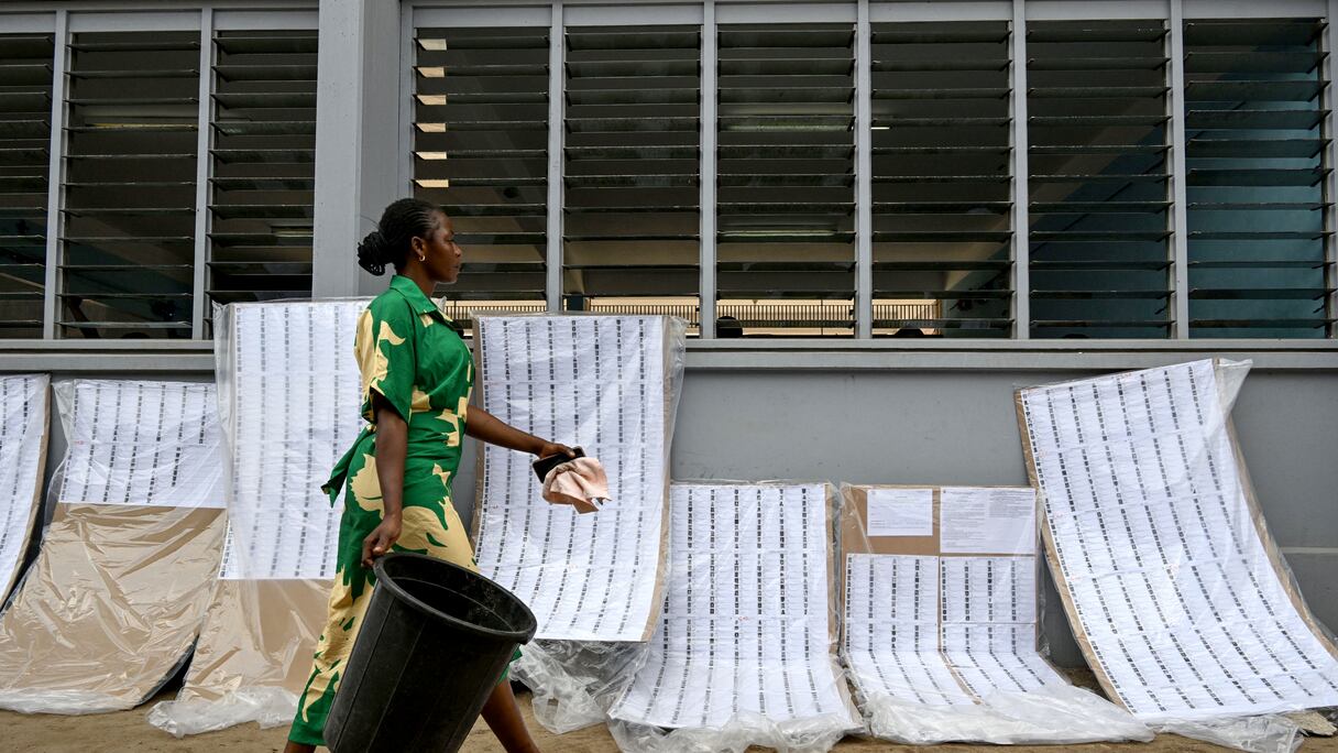 Une femme passe devant les listes électorales le 18 mars 2025 à Abidjan après que la CEI a publié la liste provisoire pour la présidentielle du 25 octobre 2025