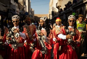 Une troupe traditionnelle gnaoua défile dans les rues lors de la cérémonie d'ouverture de la 25e édition du Festival Gnaoua et Musiques du Monde à Essaouira, au Maroc, le 27 juin 2024.