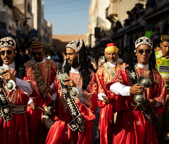 Une troupe traditionnelle gnaoua défile dans les rues lors de la cérémonie d'ouverture de la 25e édition du Festival Gnaoua et Musiques du Monde à Essaouira, au Maroc, le 27 juin 2024.