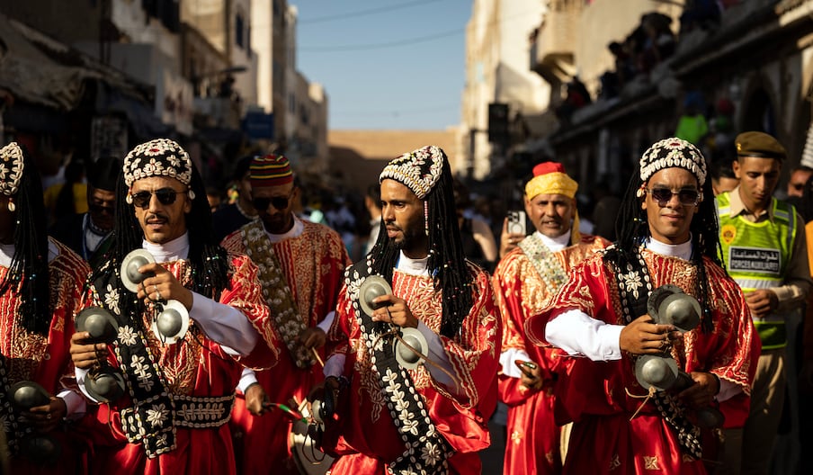 Une troupe traditionnelle gnaoua défile dans les rues lors de la cérémonie d'ouverture de la 25e édition du Festival Gnaoua et Musiques du Monde à Essaouira, au Maroc, le 27 juin 2024.