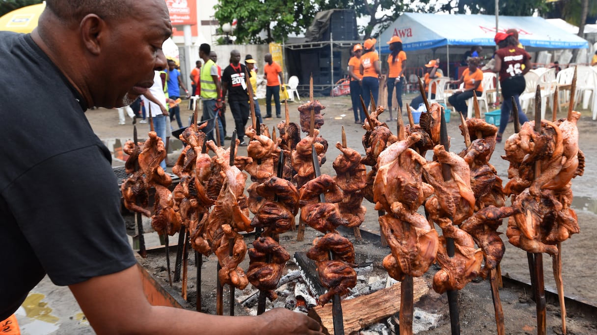 Un homme prépare du poulet braisé à Abidjan