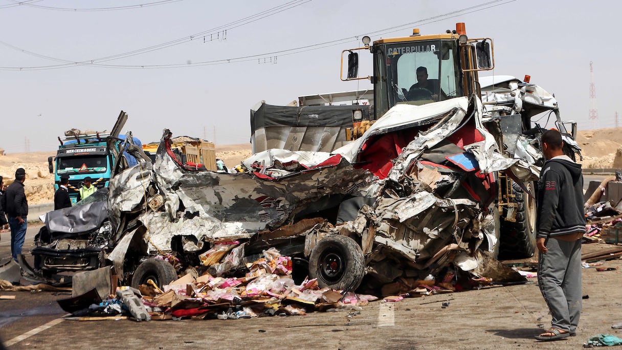 Des ouvriers enlèvent l'épave d'une voiture sur le site d'un accident de la route près de la ville d'Al-Saff, dans la province de Gizeh, au nord du Caire, à environ 40 kilomètres au nord de la capitale, le 26 mars 2020, qui a fait plusieurs morts et blessés.