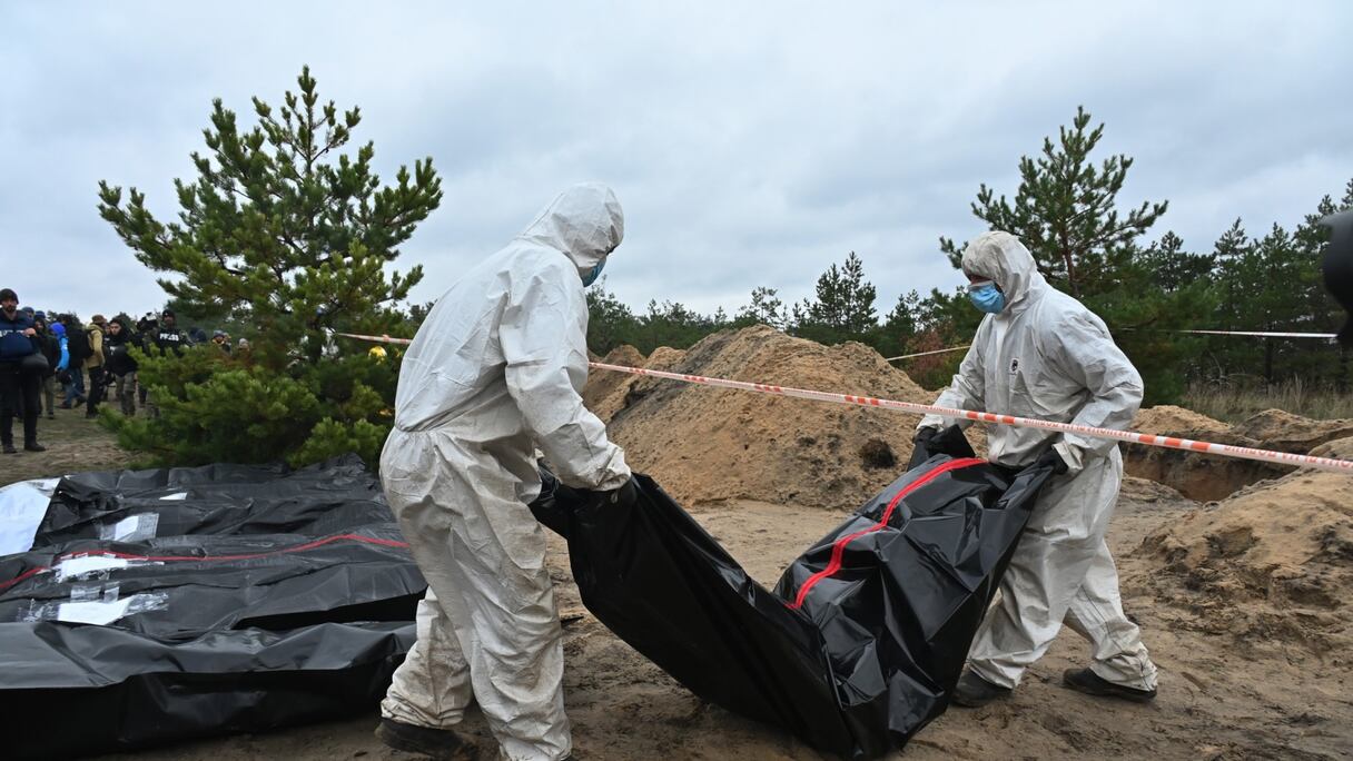La police scientifique transporte le corps de l'un des 55 soldats ukrainiens morts enterrés dans une fosse commune d'un cimetière près de Lyman, dans la région de Donetsk, le 11 octobre 2022.